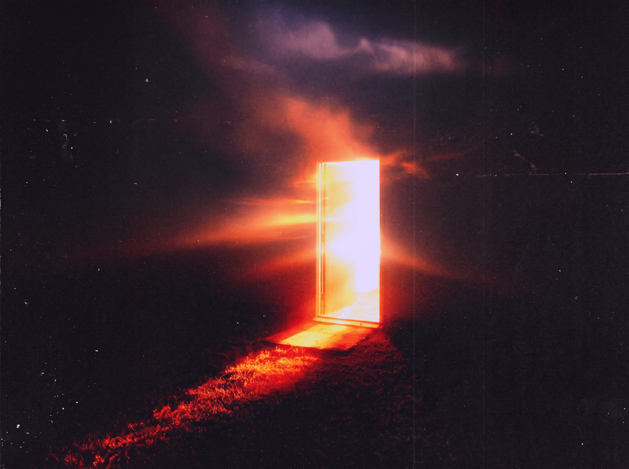 A luminous open door radiating intense orange and white light stands alone in a dark landscape under a dramatic cloudy night sky.